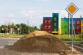 Sidewalk repair along the highway. a pile of sand for the substrate for paving slabs. The colorful house in the