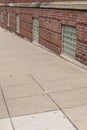 Sidewalk running directly against a red brick building with glass block basement windows