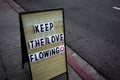 A sidewalk sign that reads `Keep the love flowing`