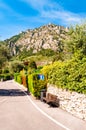 Sideway of a road with wooden bench, dead end road sign, shaped hedge on stone fence and private houses, hotels of a beautiful