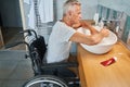 Aged man with physical disability cleaning hands in sink Royalty Free Stock Photo