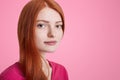 Sideways portrait of freckled serious woman with ginger hair, has healthy pure skin, poses at camera with confident expression, is