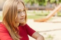 Sideways portrait of pretty young student girl with fair hair, charming eyes and freckles looking pensively into distance thinking