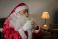 Sideways of Santa Claus relaxing in sofa at home enjoying a cup Royalty Free Stock Photo