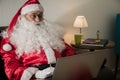 Sideways of Santa Claus relaxing in sofa at home Using laptop for communication and leisure or shopping online. Royalty Free Stock Photo