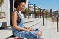 Sideways shot of black satisfied young woman checks email box on laptop computer, reads news, wears ragged denim Royalty Free Stock Photo