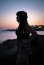 Sideways silhouette female model at sunset in a coast village