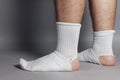 Sideways standing feet with white socks and a big hole