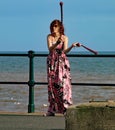 SIDMOUTH, DEVON, ENGLAND - AUGUST 5TH 2012: A young woman entertains passers by with twirling clubs by the iron railings of the