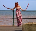 SIDMOUTH, DEVON, ENGLAND - AUGUST 5TH 2012: A young woman entertains passers by with twirling clubs by the iron railings of the