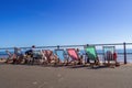 SIDMOUTH, DEVON, ENGLAND - SEPTEMBER 20 2019: People sat in deck chairs looking out across the beach towards the sea