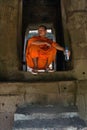 Young monk in orange robe sitting in the Angkor Wat ancient temple while holding a plastic bottle of water