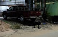 Black stray dog of mixed breed, cherry-colored Toyota brand car, trash on the street, night