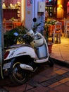 Elegant white scooter parked near a cafe, night time