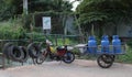 Old broken moped with a cart on which there are three blue gas bottles. Typical transport