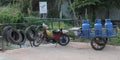 Old broken moped with a cart on which there are three blue gas bottles. Typical transport