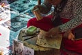 A local, cambodian woman is sitting and preparing colorful, traditional handcrafted pictures with khmer cultural motives