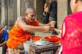 Siem Reap, Cambodia - January 30, 2017: Buddhist monk ties the blessed bracelet Angkor Wat temple