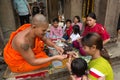 Siem Reap, Cambodia - January 30, 2017: Buddhist monk ties the blessed bracelet on kid in Angkor Wat temple, people sitting around