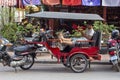 Siem Reap, Cambodia - 25 March 2018: tuk-tuk driver rests in passenger coach with mobile phone.