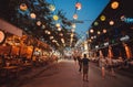 People having fun and eating dinner on main street of asian city with pubs, cafes and restaurans