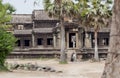 People standing on front of Angkor Wat buildind, 12th century temple under palm trees