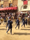 Tourists watching the colorful and fancy traditional costume parades at the horse race, Palio di Siena, held in medieval square Royalty Free Stock Photo