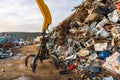 A crane clamp next to a mountain of metal waste in a junkyard.