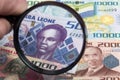 Sierra Leonean money in a magnifying glass