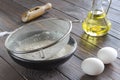 Sieve on black bowl with flour. Glass bottle with butter, eggs, wooden spoon with flour Royalty Free Stock Photo