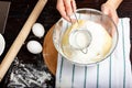 Sieve for flour in female hands. Sifting flour. Dough preparation process. A woman kneaded yeast dough for bread.