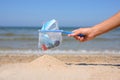 Sieve full of garbage in a female hand on the background of the sea. There is a pile of clean sand under the sieve.