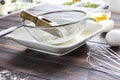 Sieve, wooden spoon and flour in white plate. Metal whisk, broken egg and eggshell. Sun`s rays on table Royalty Free Stock Photo