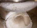 Sieving baking soda powder into a bowl.