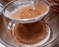 Sieving cocoa powder into a bowl.