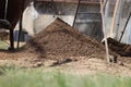 A sifting of earth through sieve. Iron shovel, iron barrel, small iron circle. Through grass on pile of clay