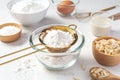 Sifting flour with gold sieve in glass bowl with baking ingredients on marble kitchen table Royalty Free Stock Photo