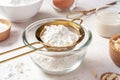 Sifting flour with gold sieve in glass bowl, closeup