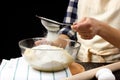Sifting flour through a sieve. The process of making yeast dough. Woman baker prepares pastry. Rustic style. Royalty Free Stock Photo