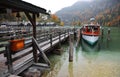 A sightseeing boat parking by the wooden pier at beautiful lakeside in a misty foggy morning on Lake Konigssee Royalty Free Stock Photo