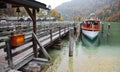 Sightseeing boat parking by a wooden pier at beautiful lakeside in a misty foggy morning on Lake Konigssee Royalty Free Stock Photo