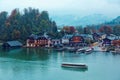 Sightseeing boats cruising on Konigssee  King`s Lake  with autumn trees & boathouses by lakeside at foggy misty blue dusk Royalty Free Stock Photo