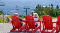 Sightseeing mountain views at Mont Tremblant ski Resort in summer. Tourists enjoying sitting at red chairs at ski resort village.