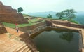 Lonely woman watching ruins of the ancient Sigiriya city with water pool and archeological area