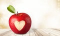 Apple with carved heart sign on wooden background