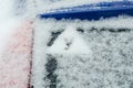 The sign of an apprentice driver on the snow-covered rear window of the automobile. A warning triangular sign with the Russian