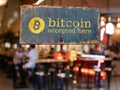 Sign bitcoin accepted here hanging in front of restaurant door.