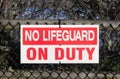 A sign on a Black fence at the beach warns `No Lifeguard on Duty` Royalty Free Stock Photo