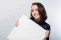 Sign board. Business woman holding white card. Isolated portrait. Young happy, smiling girl holding a blank sheet of paper for adv Royalty Free Stock Photo