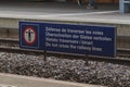 Sign board for preventing people crossing the railroad tracks, white writing on blue board with writings in different european Royalty Free Stock Photo